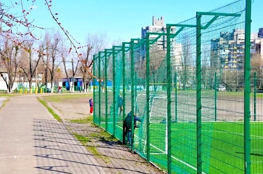 Fencing of sports grounds with dampening mesh